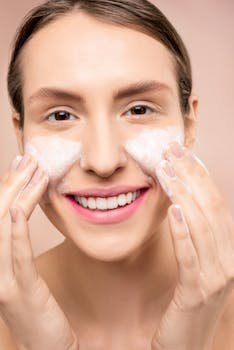 Close-up of a woman happily washing her face with foamy cleanser.