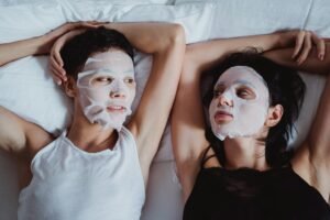 Two people enjoying a facial sheet mask skincare ritual together indoors.